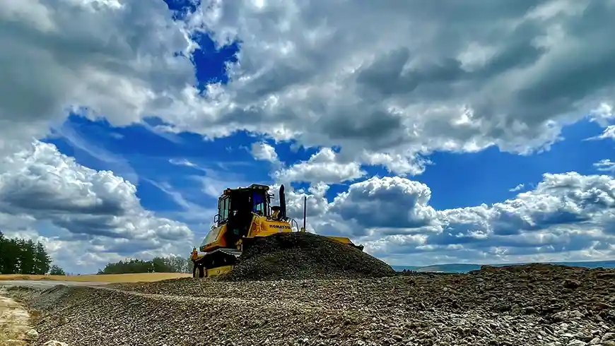 Wegebau, gelber Bagger auf Acker
