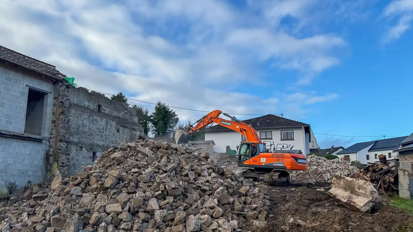 Baureifmachung, orangener Bagger auf Schutt